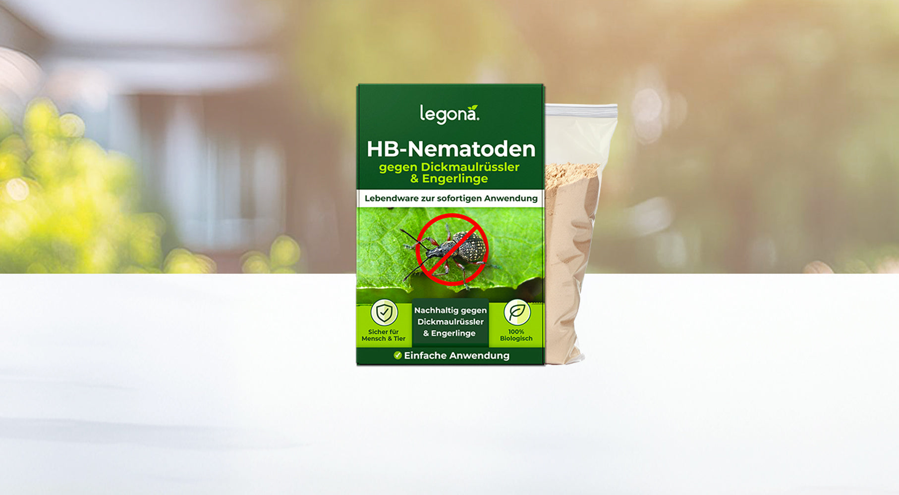 Verpackung von Legona HB-Nematoden gegen Dickmaulrüssler und Engerlinge mit grünem Etikett und Symbolen für nachhaltige Anwendung und einfache Nutzung vor unscharfem Garten-Hintergrund